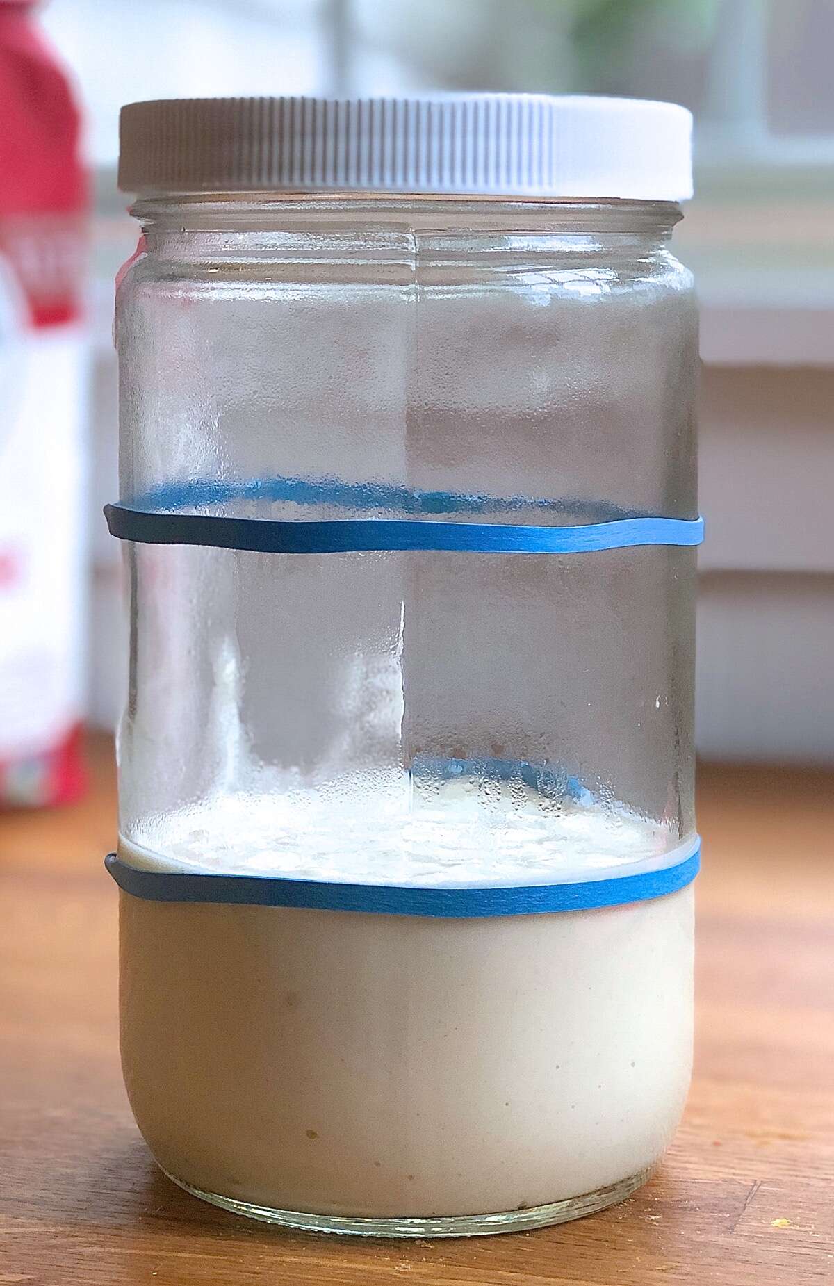 Sourdough starter in a glass jar on a counter, unrisen.