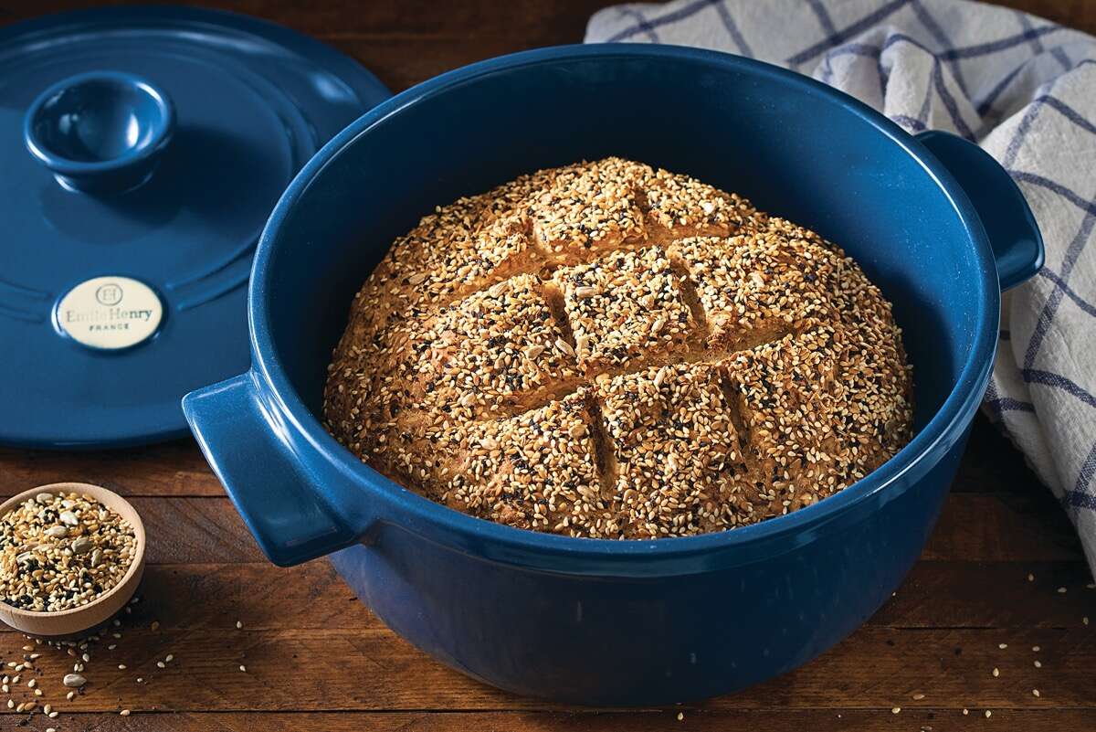 Round loaf of seeded sourdough bread baked in a Dutch oven.