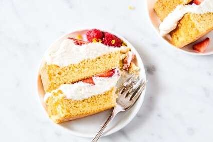 Yellow genoise cake filled with strawberries and whipped cream, slice on a plate.