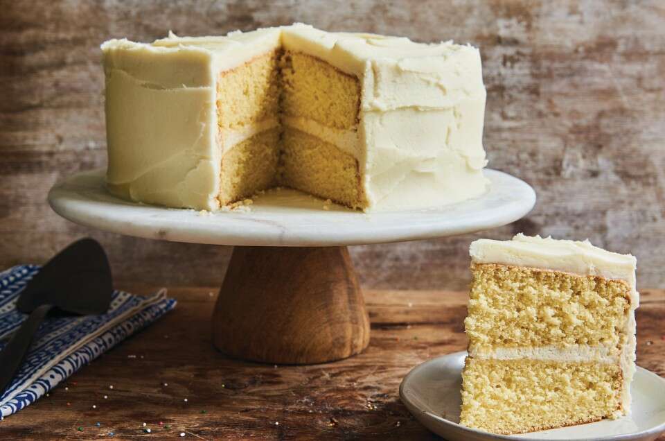 Slice of Golden Vanilla Cake, with full cake in background