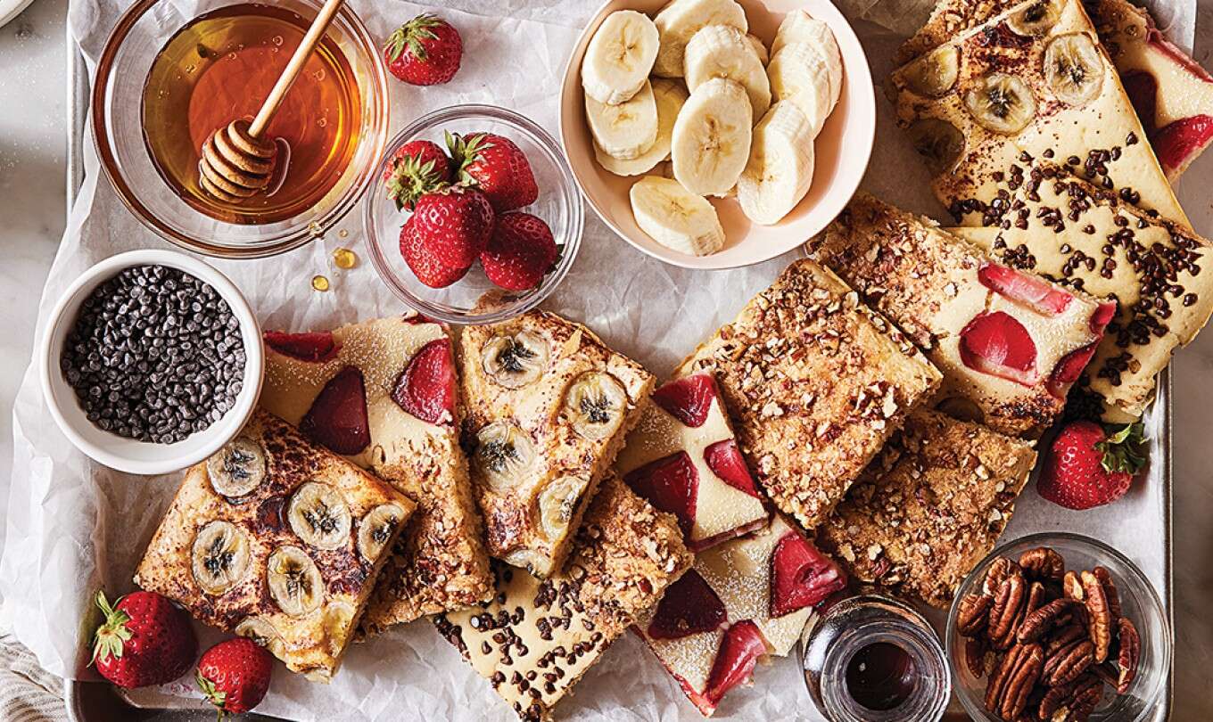 A platter of sheet pan pancakes with different toppings set in a breakfast scene